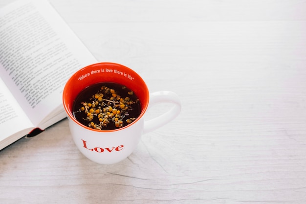 Becher mit Tee in der Nähe von Buch