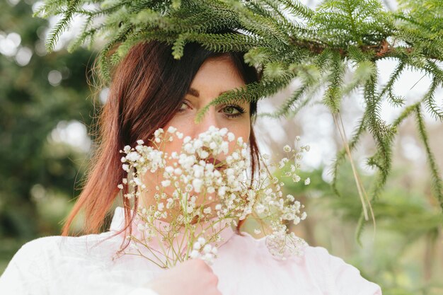 Bedeckungsgesicht der jungen Frau mit Blumen