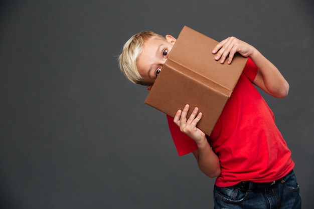 Kostenloses Foto bedeckungsgesicht des kleinen jungen kindermit buch.