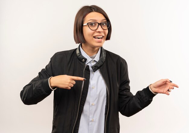 Beeindrucktes junges Callcenter-Mädchen, das eine Brille trägt, die auf Seite lokalisiert auf Weiß zeigt