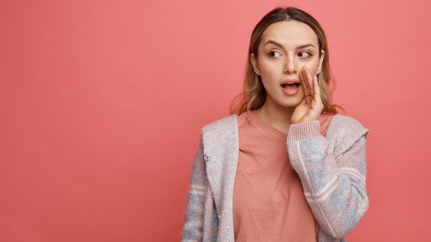 Beeindrucktes junges Mädchen, das seitliches Flüstern betrachtet