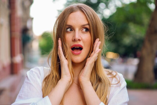 Beendet überraschte elegante blonde Frau posinf auf der Straße, Frühlingssommerzeit, natürliches Make-up.