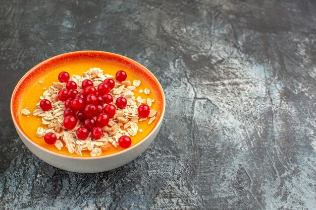 Beerenbeeren der Seitennahansichtbeeren in der orangefarbenen Schüssel auf der linken Seite des grauen Tisches