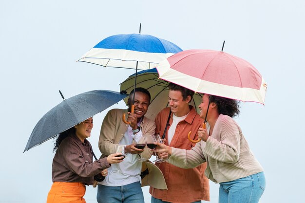 Begleiter, die Wein unter Regenschirmen während der Party im Freien trinken