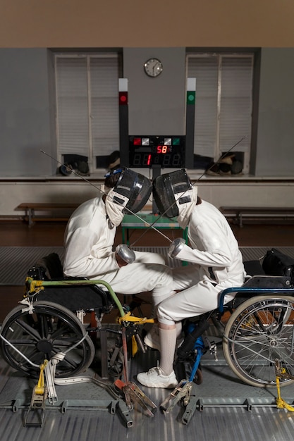 Kostenloses Foto behinderte fechter in spezialausrüstung, die aus ihren rollstühlen kämpfen