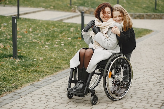 Behinderte Frau im Rollstuhl mit Tochter. Familie, die draußen im Park spazieren geht.