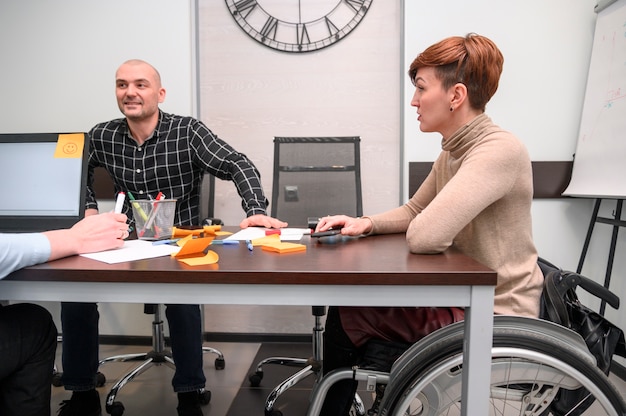 Behinderte junge Frau im Büro am Schreibtisch