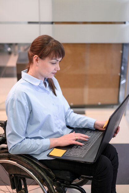 Behinderte junge Frau im Büro, die Laptop betrachtet