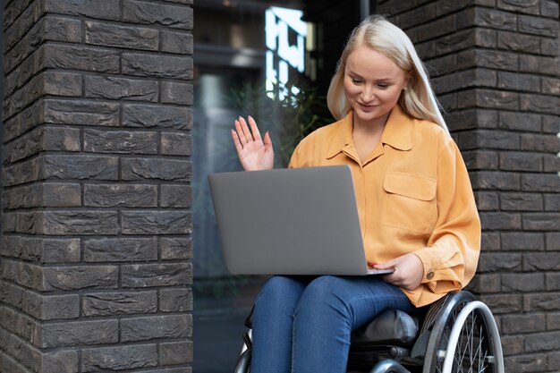 Behinderte Person im Rollstuhl arbeitet am Laptop