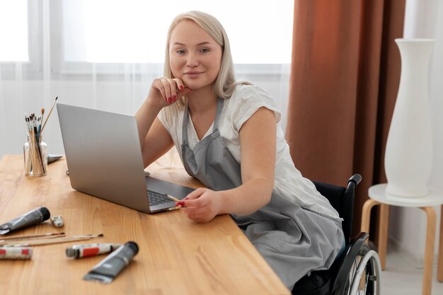 Behinderte Person im Rollstuhl arbeitet am Laptop