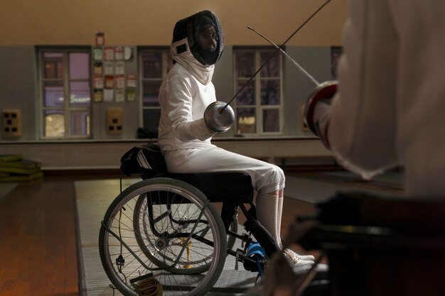 Behinderter Fechter in Spezialausrüstung im Rollstuhl sitzend