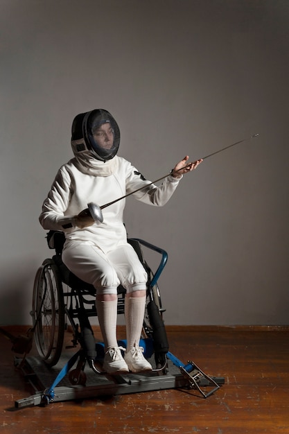 Behinderter Fechter in Spezialausrüstung im Rollstuhl sitzend