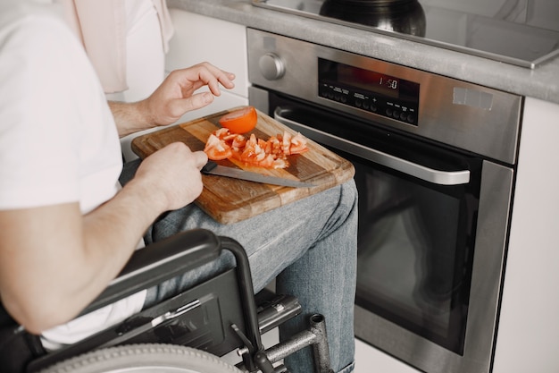 Behinderter Mann, der Essen in der Küche zubereitet. Gemüse schneiden.