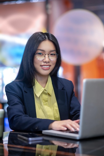 Bei der Arbeit. Asiatische Geschäftsfrau im Büro, die an einem Laptop arbeitet