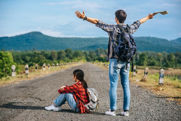 Beide männlichen Touristen stehen auf beiden Seiten und heben die Hände. Weibliche Touristen sitzen auf der Straße