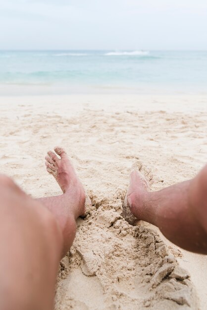 Beine des Nahaufnahmemannes am Strand