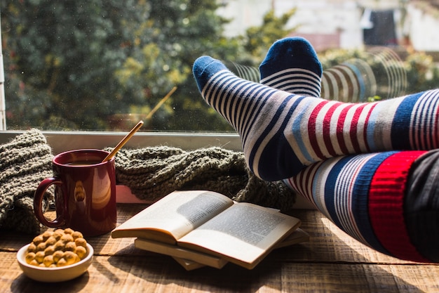 Beine in gestreiften Socken in der Nähe von Fenster