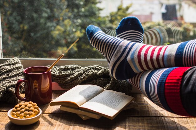 Beine in gestreiften Socken in der Nähe von Fenster