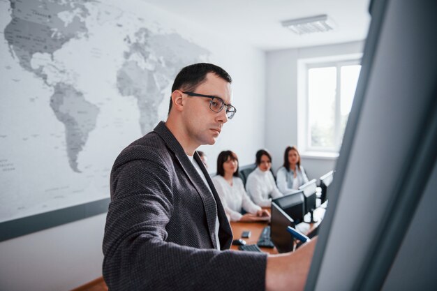 Beispiel auf dem Whiteboard zeigen. Gruppe von Personen an der Geschäftskonferenz im modernen Klassenzimmer tagsüber