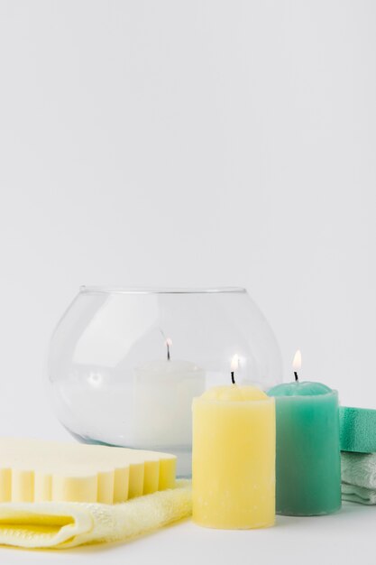 Beleuchtete bunte Kerzen mit Schwamm und Serviette gegen weißen Hintergrund