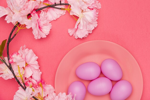 Bemalte Eier auf Teller mit Blume daneben