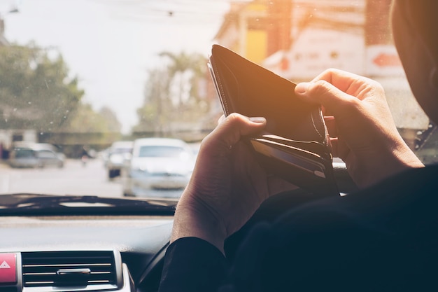 Bemannen Sie Blick auf seine leere Geldbörse beim Fahren des Autos, gefährliches Verhalten