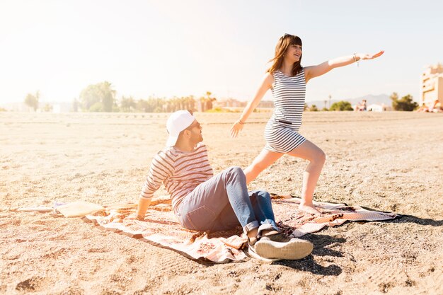 Bemannen Sie das Betrachten der jungen Frau, die auf Strand trainiert