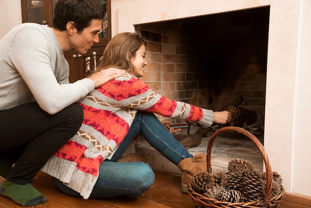 Kostenloses Foto bemannen sie das betrachten der jungen frau, die pinecone in den kamin setzt