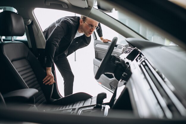 Bemannen Sie das Betrachten eines Autos in einem Autosalon