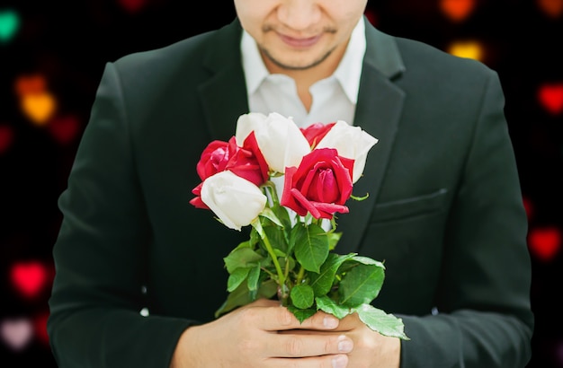 Bemannen Sie das Geben roten und weißen Blumenstraußrosen jemand am Valentinstag