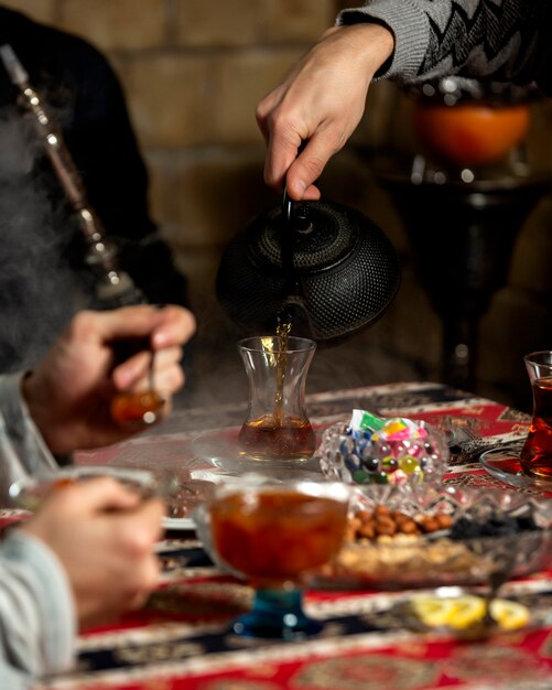 Bemannen Sie das Gießen des Tees in Armudu-Glas in der aserbaidschanischen traditionellen Teeeinrichtung