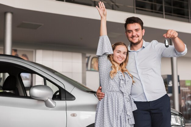 Bemannen Sie das Halten von Autoschlüsseln und von Frau, die ihre Hand anheben