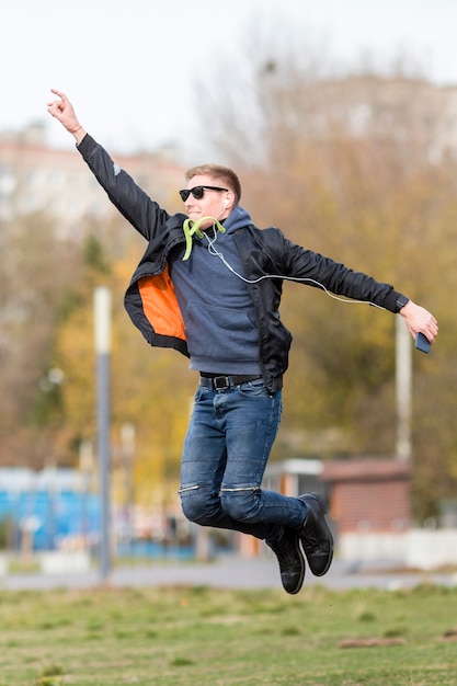 Bemannen Sie das Hören Musik auf Kopfhörern beim draußen springen