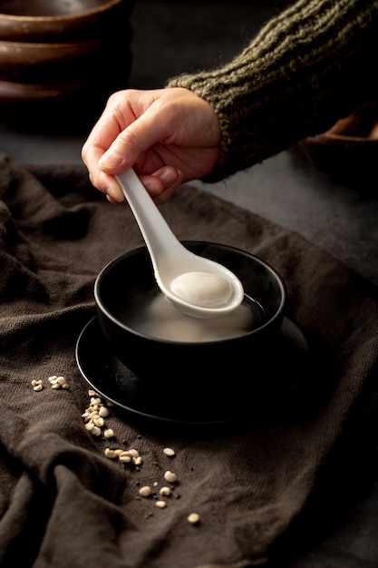 Bemannen Sie das Nehmen eines Löffels Suppe von einer schwarzen Schüssel