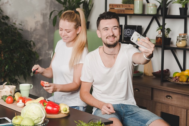 Bemannen Sie das Nehmen von selfie ihrer Freundinausschnitttomatenscheibe