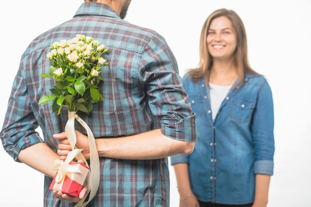 Bemannen Sie eine Geschenkbox und eine Blume hinter seinem zurück verstecken, der der Freundin Überraschung gibt