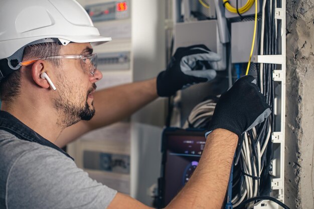 Bemannen Sie einen Elektrotechniker, der in einer Schalttafel mit Sicherungen arbeitet