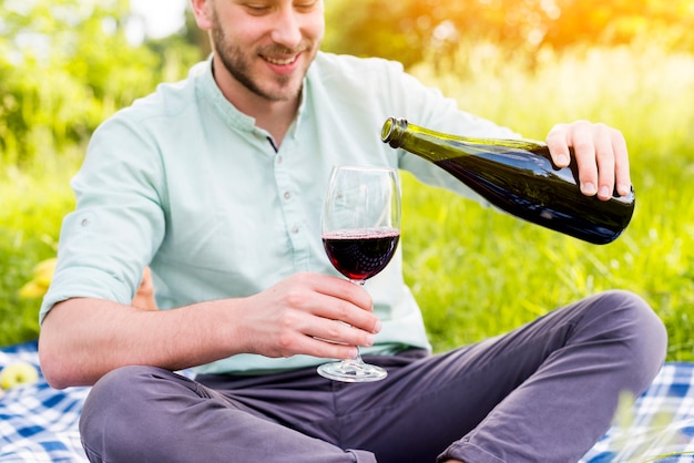 Bemannen Sie strömenden Wein in Glas auf Picknick