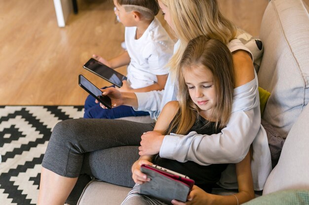 Bemuttern Sie und ihre Kinder, die ihre hohe Ansicht der Telefone betrachten