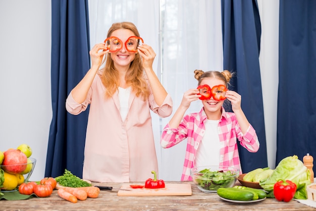 Kostenloses Foto bemuttern sie und ihre tochter, die roten grünen pfeffer vor ihrem haus hält