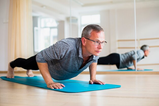 Übende Yogapositionen des erwachsenen Mannes