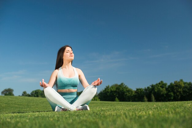 Übendes Yoga der athletischen Frau im Freien