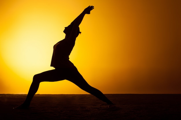Übendes Yoga der Frau im Sonnenunterganglicht