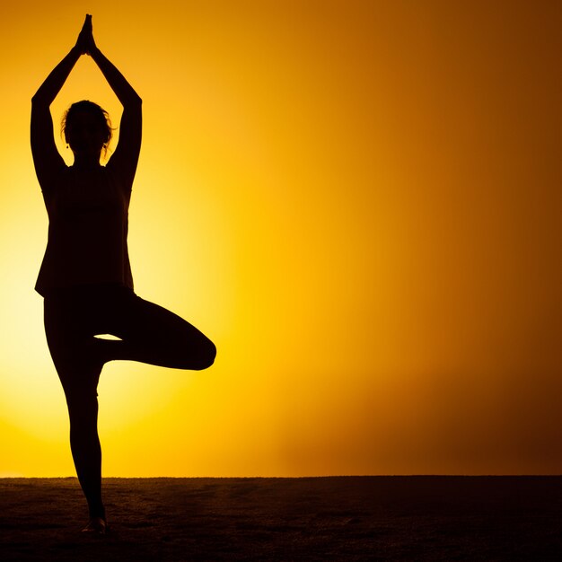 Übendes Yoga der Frau im Sonnenunterganglicht