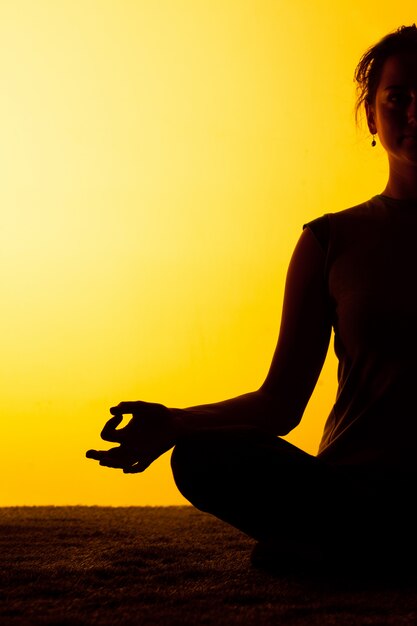 Übendes Yoga der Frau im Sonnenunterganglicht