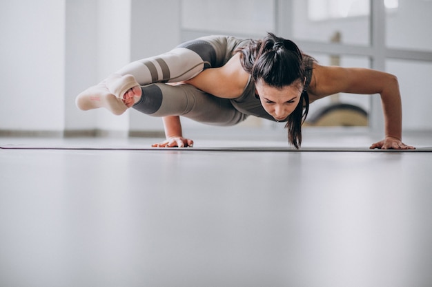 Übendes Yoga der Frau in der Turnhalle auf einer Matte