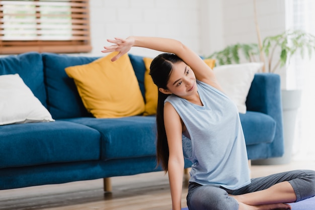 Übendes Yoga der jungen Asiatin im Wohnzimmer.