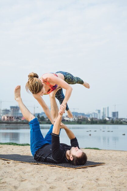 Übendes Yoga der jungen Paare auf Stadthintergrund