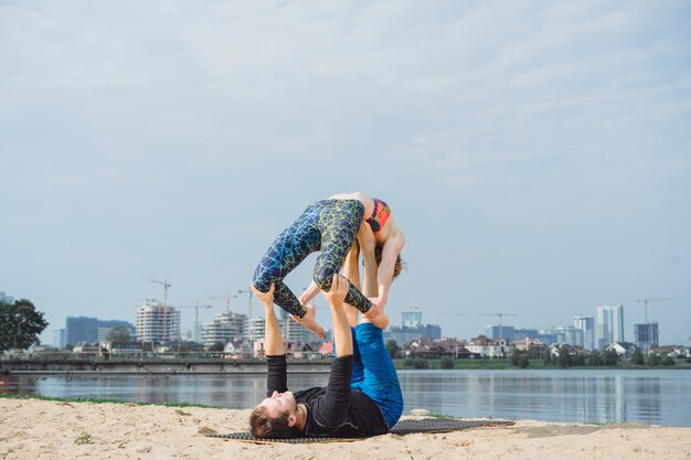 Übendes Yoga der jungen Paare auf Stadthintergrund