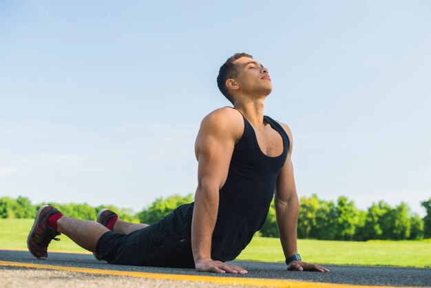 Übendes Yoga des athletischen Mannes im Freien